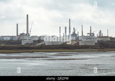 Chimneys and Oil Storage Tankers at ChemicalX Oil Refinery in Fawley, Southampton, England, view from boat. Stock Photo