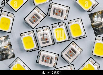Electronic light-emitting diodes on white circuit board of household LED bulb. Closeup of yellow or clear light sources of different color temperature. Stock Photo