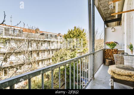 Panorama of houses with trees and lanterns from a narrow brick balcony with metal railings and a wooden chair Stock Photo