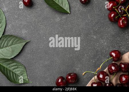 Frame made of ripe cherry and green leaves on dark background Stock Photo