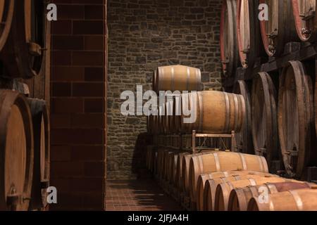 The ambiance of the traditional wine cellar, aging red wine barrels, wooden casks in rows in the winery underground storage room Stock Photo