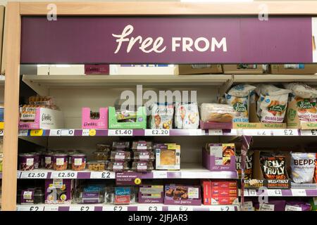 A gluten free aisle with gluten free products on shelves with a 'Free From' advertising board at a Tesco supermarket in Basingstoke, UK Stock Photo