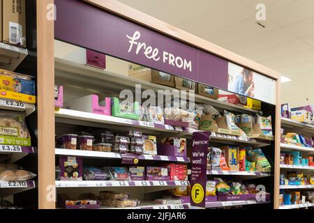 A gluten free aisle with gluten free products on shelves with a 'Free From' advertising board at a Tesco supermarket in Basingstoke, UK Stock Photo