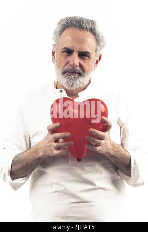50s grey haired bearded man holds heart shaped balloon by heart isolated white background medium shot . High quality photo Stock Photo