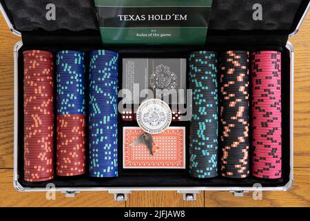 A metallic poker case with betting chips, packs of playing cards and a dealer token for playing Texas Hold 'em. Theme - poker, gambling at home Stock Photo
