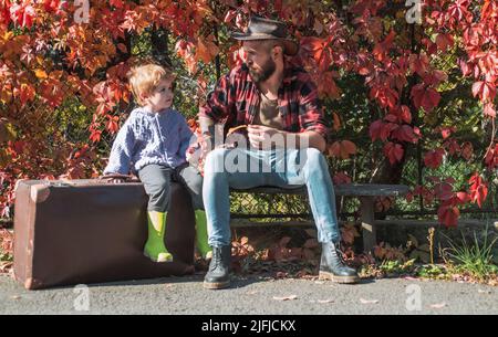 Cute little boy with his father during stroll in the forest. Dad and son in the autumn park play laughing. Childhood concept. Atumn fun at the park Stock Photo