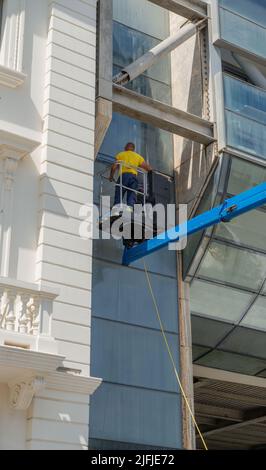 Cattolica Italy 24 June 2022: Glass cleaner in the shopping center using the mobile platform to reach the upper parts of the building Stock Photo