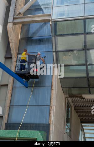 Cattolica Italy 24 June 2022: Glass cleaner in the shopping center using the mobile platform to reach the upper parts of the building Stock Photo