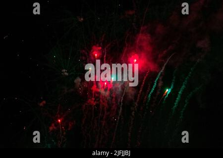 Flying up, volleys of fireworks, red and green, against the background of haze and the night sky. High quality photo Stock Photo