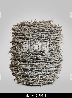 roll of old unused twisted barbed wire with dirt isolated on a neutral gray background Stock Photo