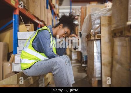 Tired stress woman worker labor working in warehouse cargo inventory industry. Stock Photo