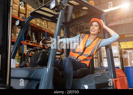 Happy woman worker warehouse staff forklift driver happy smiling enjoy working Asian people. Stock Photo