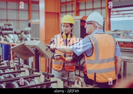 Senior Engineer Training Heavy Industry Worker workman service team working in metal factory. Stock Photo