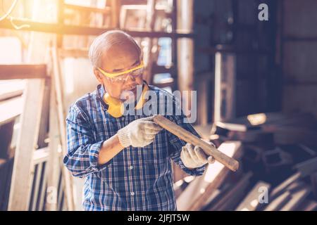 Senior Carpenter man Wood worker working hand made furniture in shop factory industry. male wooden craftsman builder working in workshop. Stock Photo