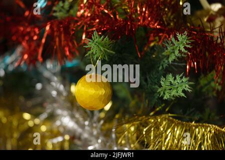 Close-up of a fully decorated Christmas tree with a prominent red heart shaped bauble surrounded by multicoloured tinsel. Stock Photo