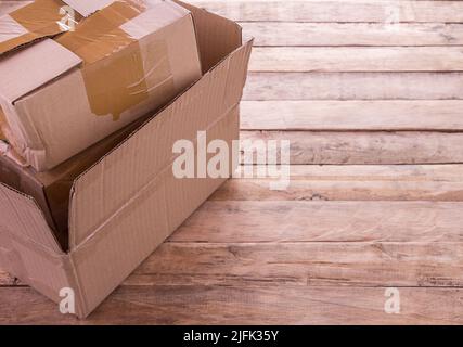 Empty opened brown old cardboard box for mock up on bright wooden table with copy space for design Stock Photo
