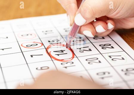 close up on employee woman hand using red pen to writing schedule on calendar 2022 to make an appointment meeting or manage timetable each day at hous Stock Photo