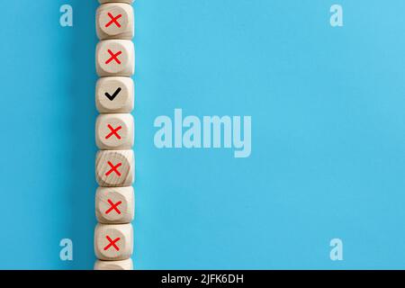 Wooden cube with checkmark right symbol stands out among the wooden cubes with wrong cross symbol. Making the right decision in business concept. Stock Photo