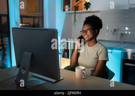 Remote female developer chatting on smartphone, enjoying flexible freelance schedule Stock Photo