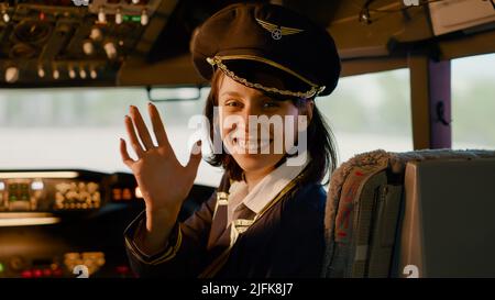 Portrait of woman airline copilot in command to fly airplane, sitting in aircraft cockpit. Using dashboard navigation compass with buttons and lever, control panel indicators. Stock Photo