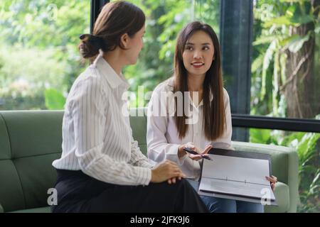 Coworker business concept, Businesswomen hold document to explaining about new project to colleague. Stock Photo