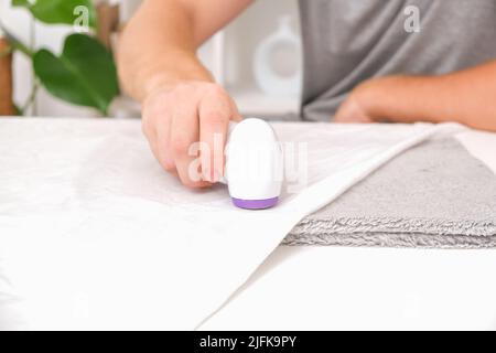 The man removes fabric pills using lint shaver. Stock Photo