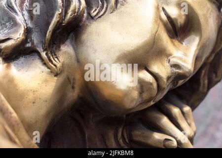Vintage sculpture of sad woman in grief. Virgin Mary bronze statue. Religion, faith, suffering, death concept. Stock Photo