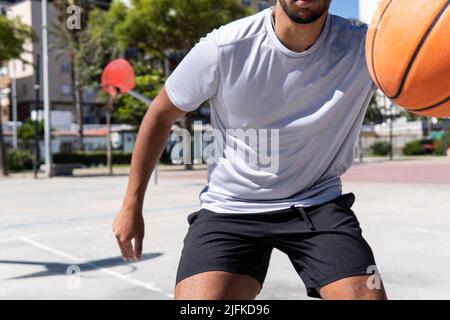 Close up view of an unrecognizable young muslim man playing basketball in the street, city life and training and sport concept Stock Photo
