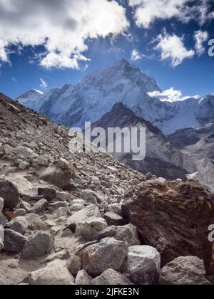 Trekkers follow the rocky path along the Khumbu Glacier's moraine below Nuptse Nup II (7732m) on the Everest Base Camp route near Gorak Shep. Stock Photo