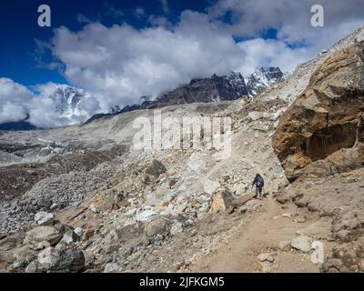 Trekkers and porters returning from Everest Base Camp to Gorak Shep along the moraine of the Khumbu Glacier. Stock Photo