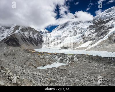 Low May clouds shroud the peaks above the coloured tents of Everest Base Camp clustered at the edge of the Khumbu Icefall Stock Photo