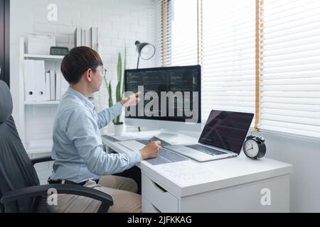 Software development concept, Male programmer checking data codes on document and computer screen. Stock Photo