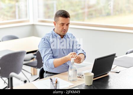 man using hand sanitizer at home office Stock Photo