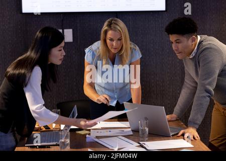 Multiracial professional analyzing sales reports and brainstorming in meeting room at office Stock Photo