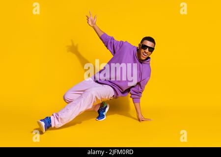 Full length body size view of attractive cheerful guy dancing low brake clubbing isolated over bright yellow color background Stock Photo