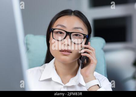 Photo close-up portrait Asian business woman talking on the phone, young office worker at work. Stock Photo