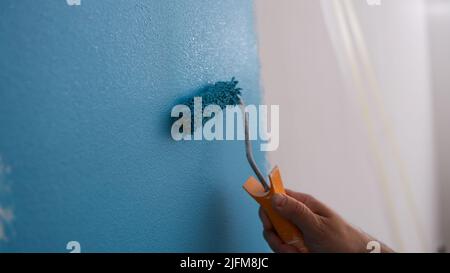 Male decorator painting wall in blue color Stock Photo