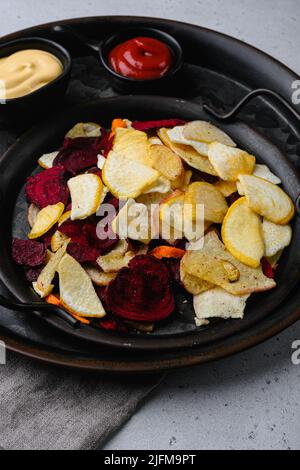 Dried vegetables chips, on gray stone table background Stock Photo