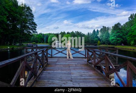 A girl stands on a bridge in Europe on a clear sunny day in summer. Back view of a girl. Stock Photo