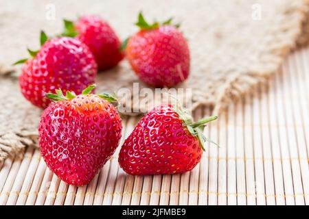 Fresh strawberries on sack with wooden background Stock Photo