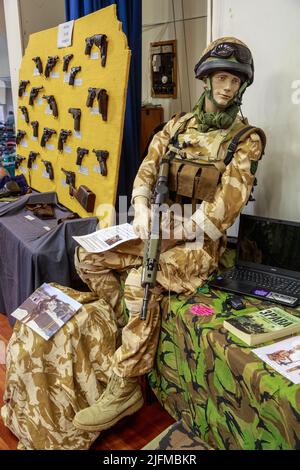 A mannequin dressed as a British paratrooper sits next to a collection of WWI pistols at a gun show. Tauranga, New Zealand Stock Photo