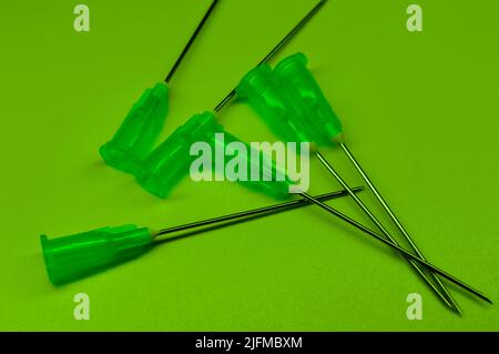 Medical syringe's needles compilation on a green background. Social problems.  Drugs and medical treatment. Stock Photo