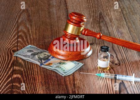 Judges hammer, Dollar notes, syringe and vaccine bottle on a wooden background. Concept for a medical judgment. High quality photo Stock Photo