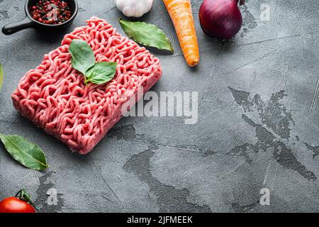 Ingredients for cooking Bolognese sauce, minced beef meat tomatoe and herbs, on gray stone background, with copy space for text Stock Photo