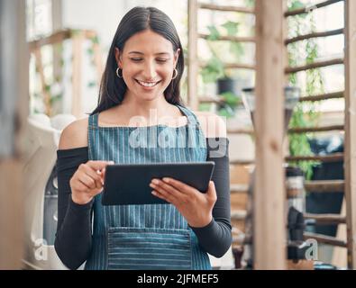 Shot of one young hispanic waitress using a digital tablet device while working in a store or cafe. Happy woman planning and browsing online while Stock Photo