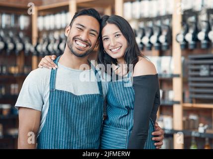 Portrait of a happy young hispanic man and woman working in a store or cafe. Friendly couple and coffeeshop owners managing a successful restaurant Stock Photo
