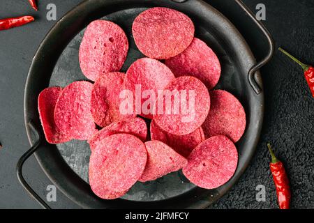Red potato chips on black dark stone table background, top view flat lay Stock Photo
