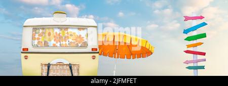 Retro caravan with beach umbrella and colorful wooden direction sign post Stock Photo