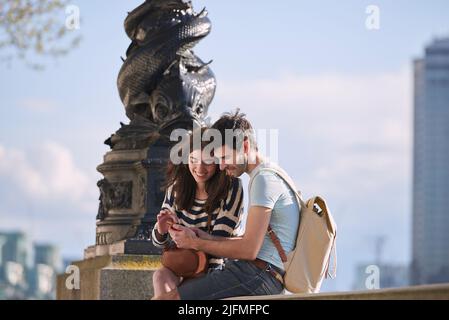 Who needs a map with this awesome app. Shot of a young couple using a smartphone while exploring the city of London. Stock Photo