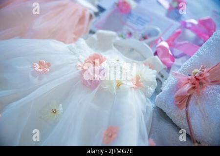 Baptism pictures. White gown baby with pink flowers outfit for religious celebration after birth. High quality photo Stock Photo